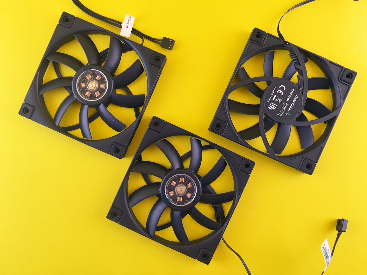 our-services-2 Three black computer cooling fans arranged on a vivid yellow backdrop, perfect for tech themes.